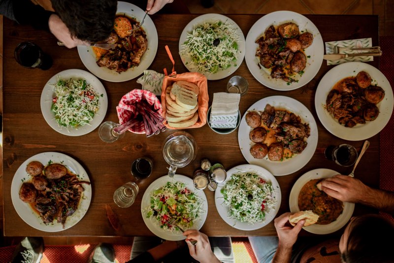 Family sharing plates of food around a large wooden table